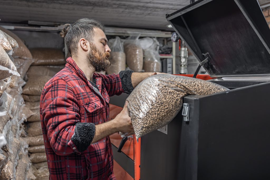 The man loads the pellets in the solid fuel boiler, working with biofuels.