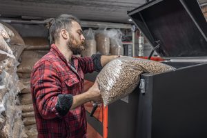 The man loads the pellets in the solid fuel boiler, working with biofuels.